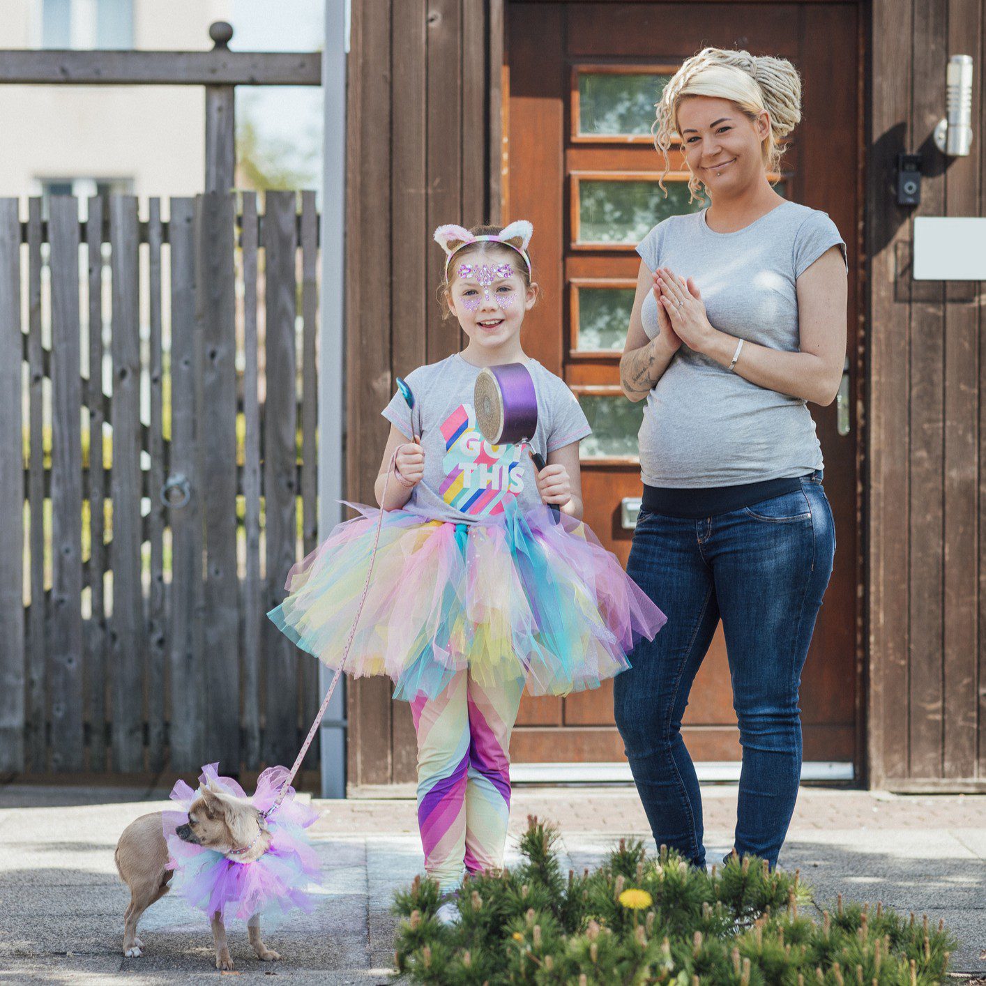 Child in rainbow costume with smiling woman.