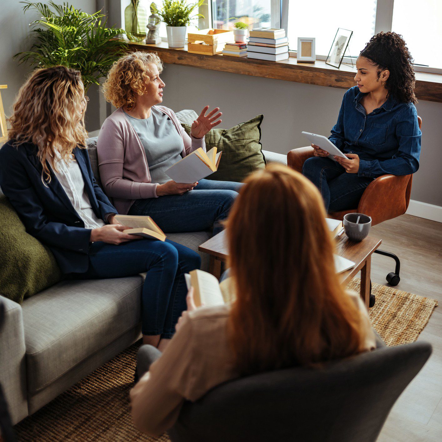 Group discussing books in cozy living room.