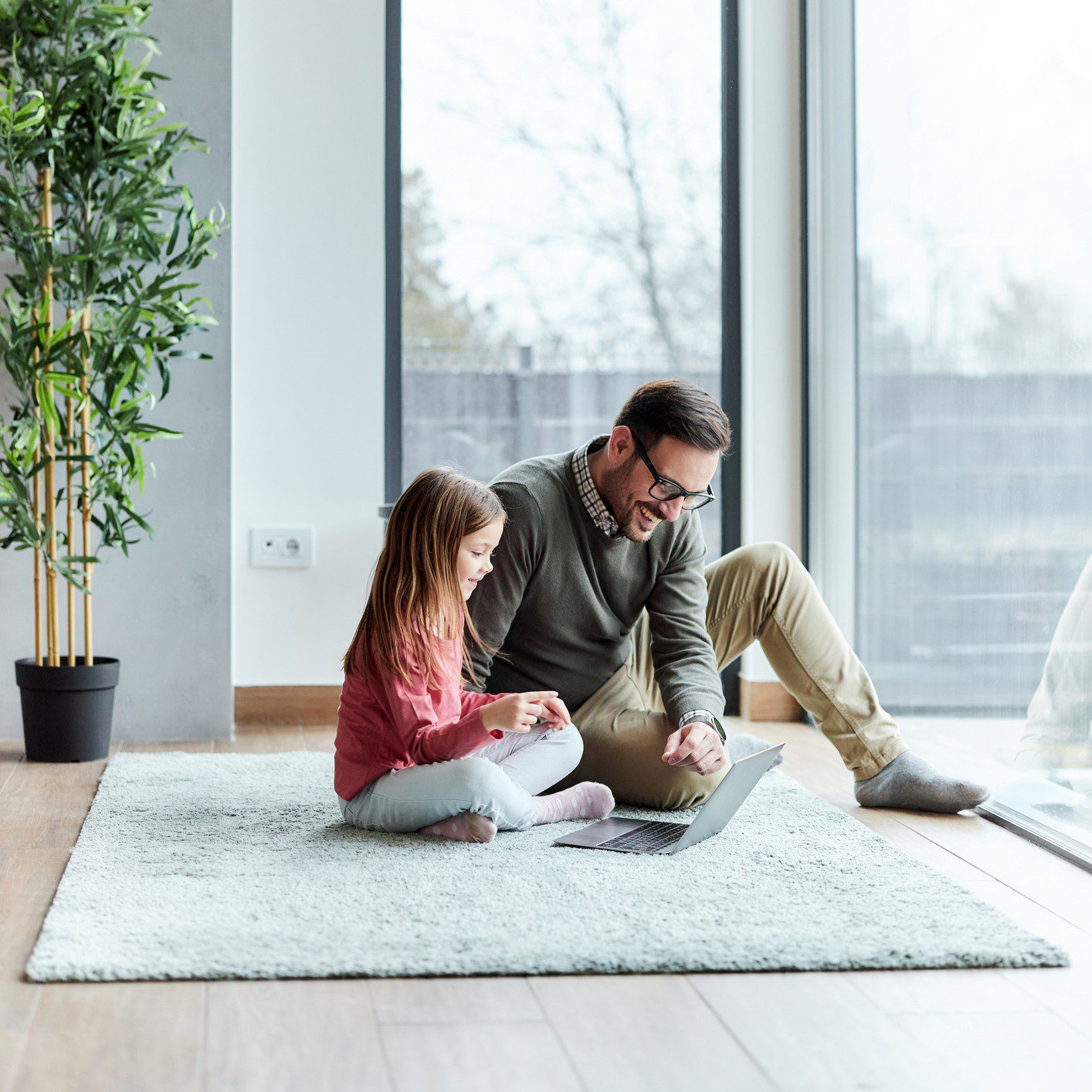Father and daughter using laptop together indoors.