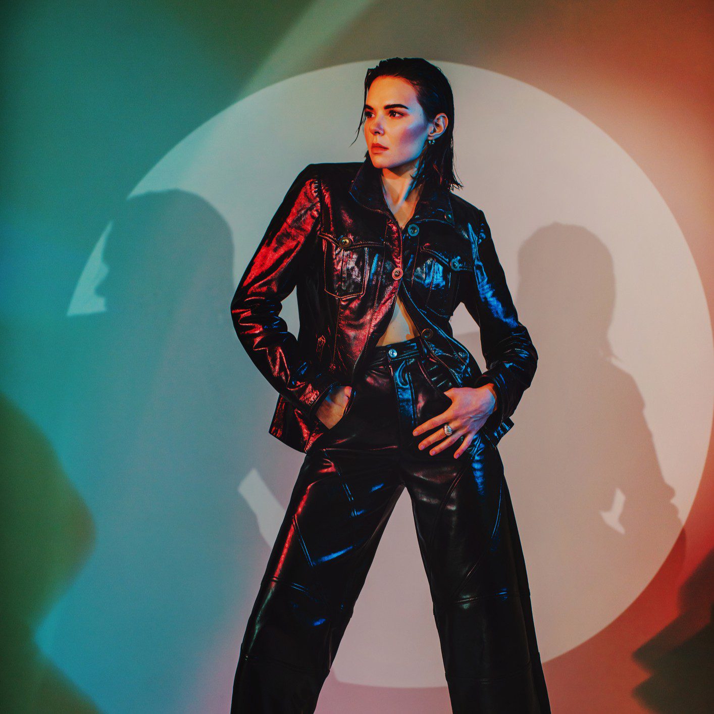 Person in leather outfit with colorful lighting.