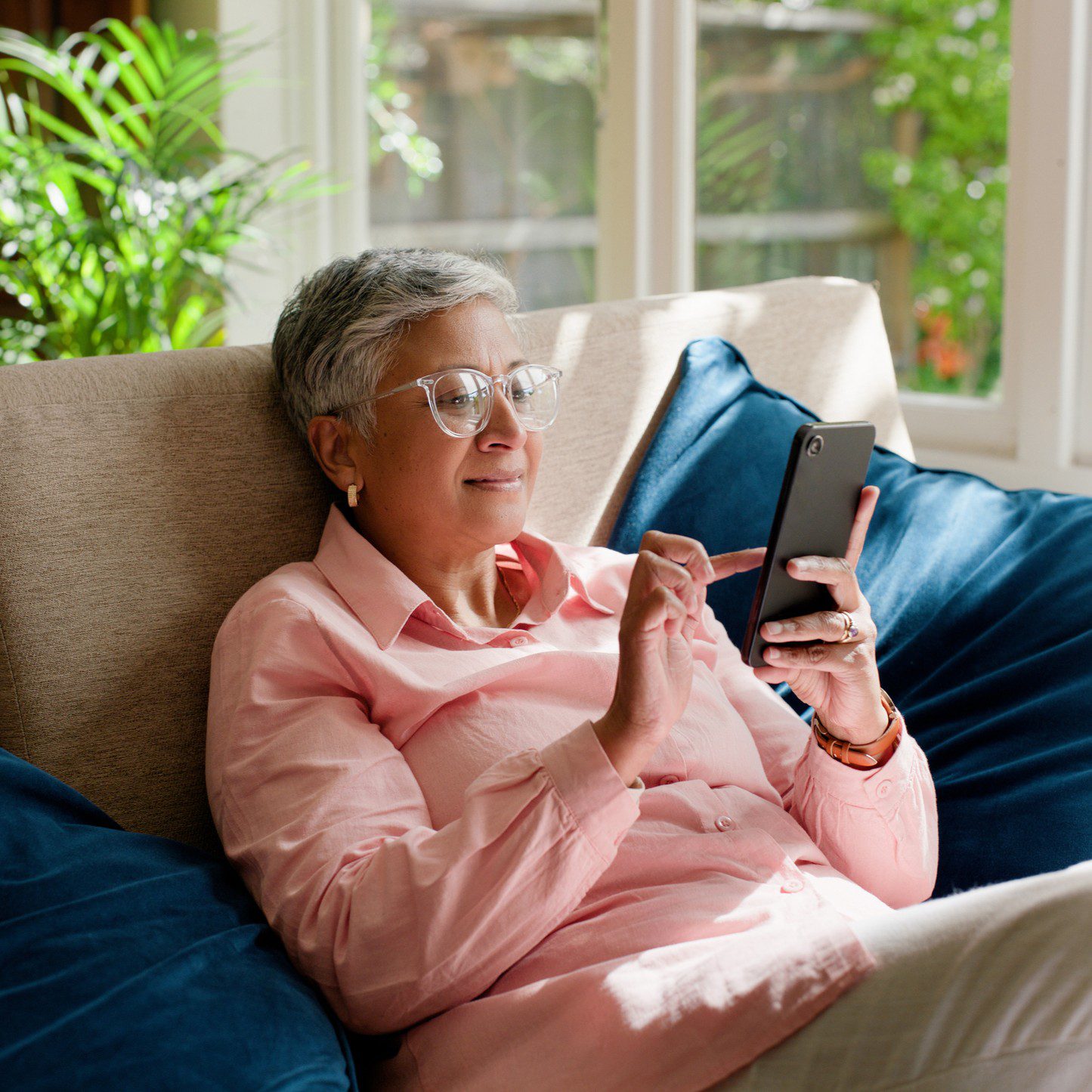 Woman using smartphone on a comfortable sofa.