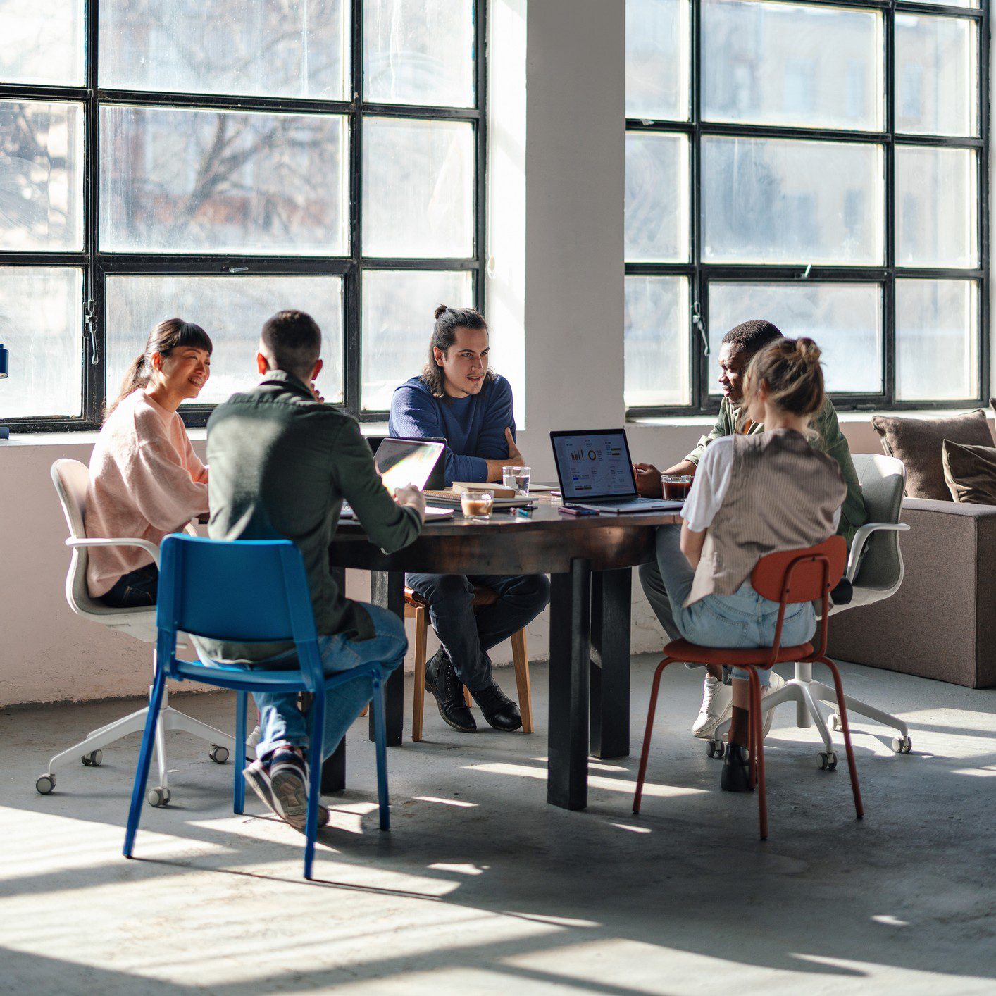 People collaborating around a table with laptops.