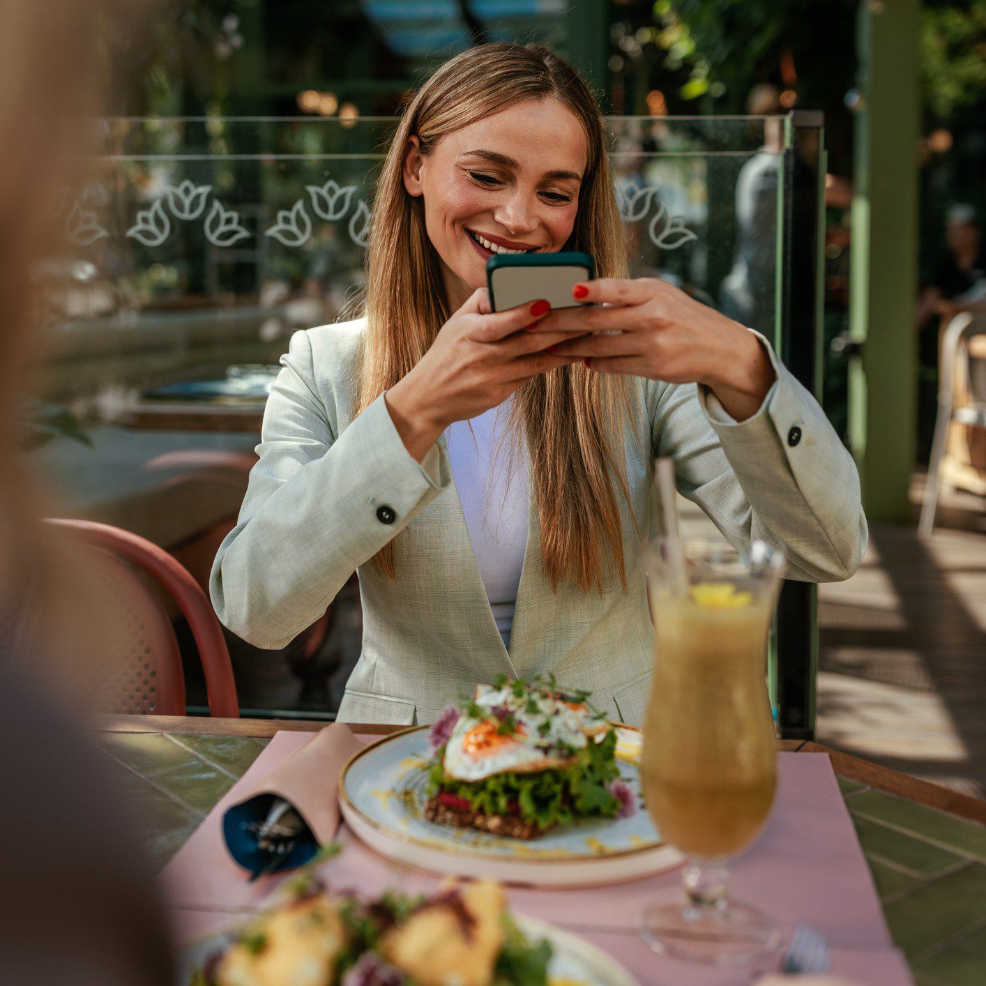 Woman photographing food at an outdoor cafe.