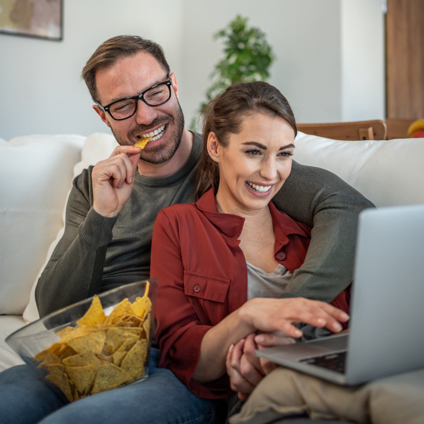 Couple laughing while watching laptop together.