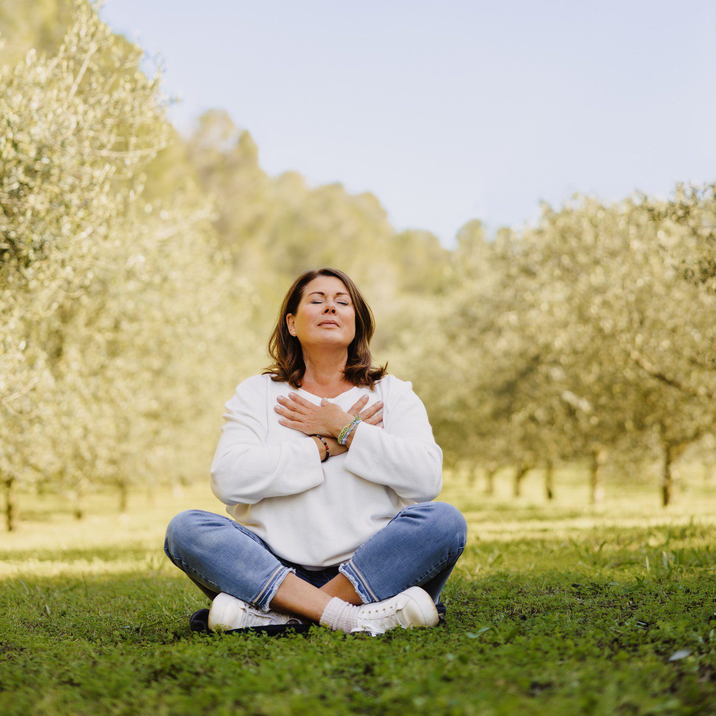 Woman meditating in peaceful outdoor setting.