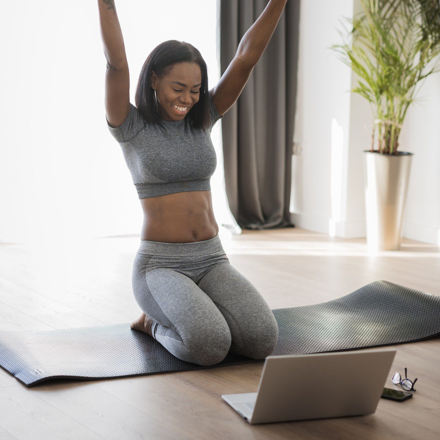 Woman celebrating success on exercise mat indoors.