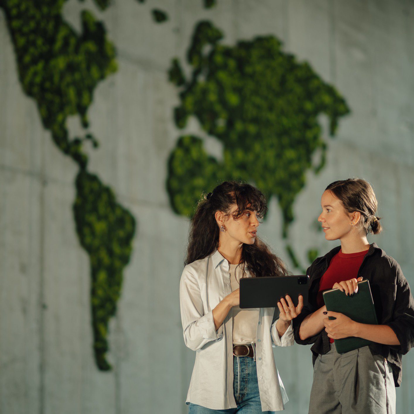 Two women talking in front of map.