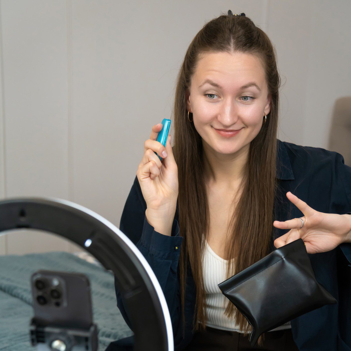 Woman recording makeup tutorial with smartphone.
