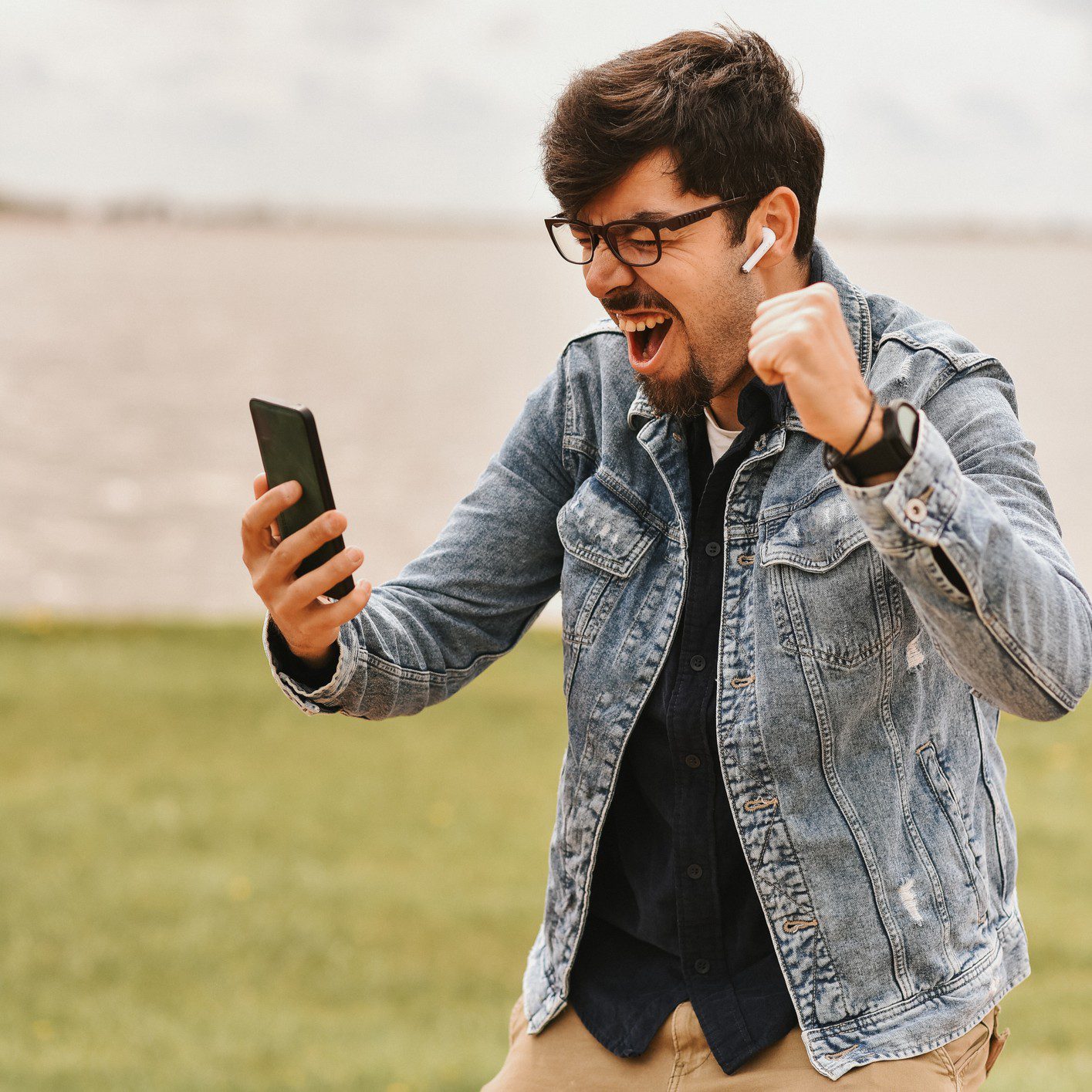 Man celebrating while looking at his phone.