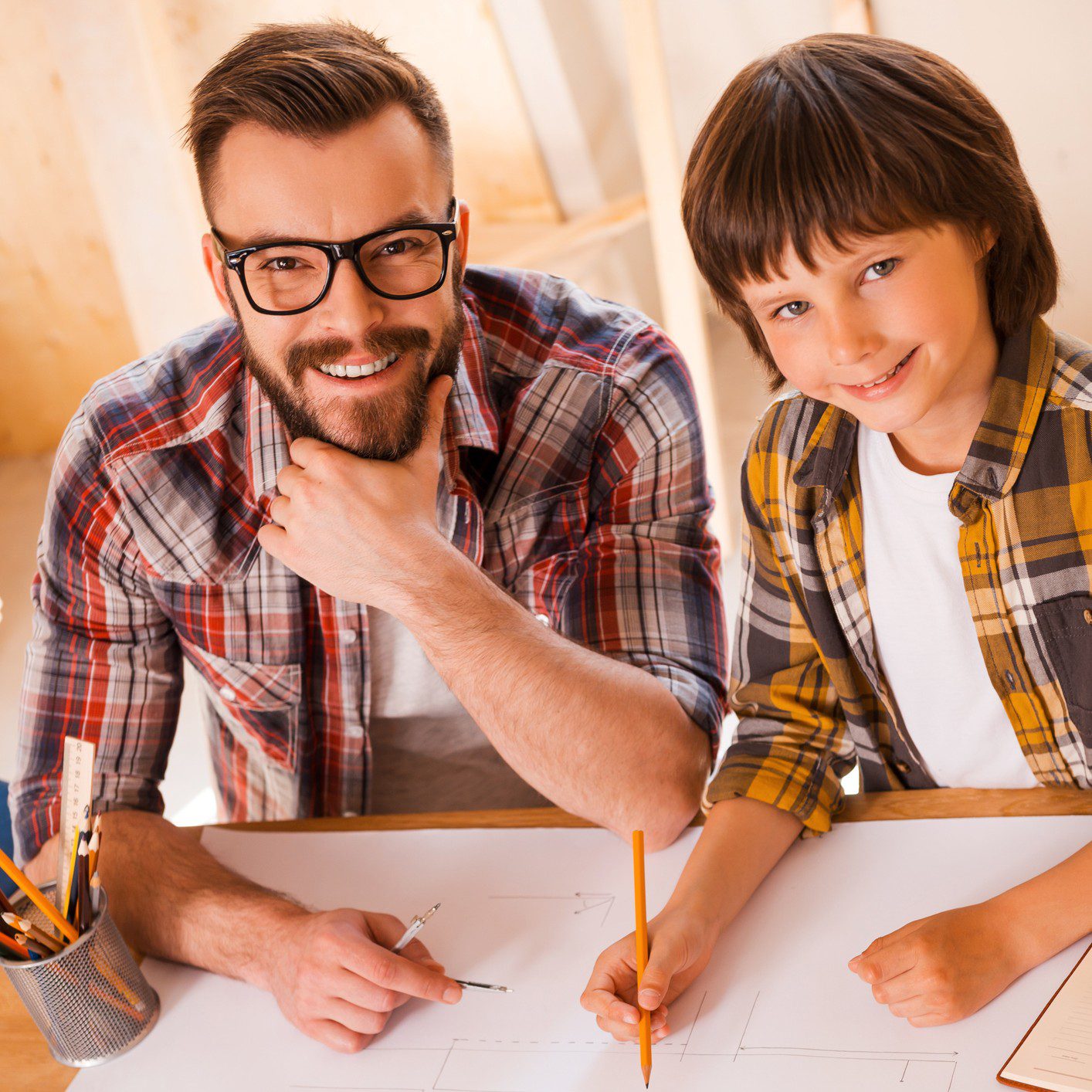 Father and son drawing together, smiling happily.