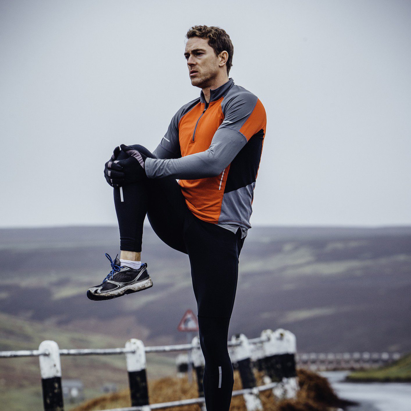 Man stretching outdoors in athletic gear.