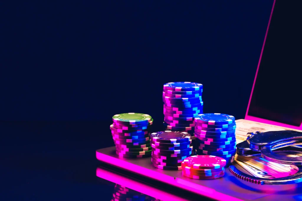 Stacks of colorful poker chips on a casino table under neon lights.