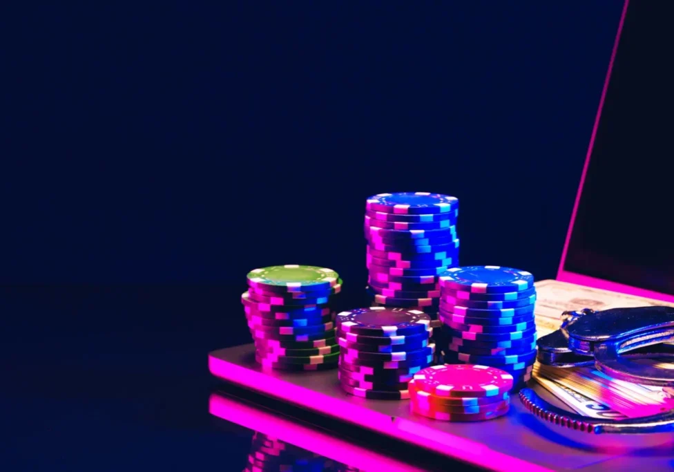 Stacks of colorful poker chips on a casino table under neon lights.